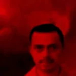 Retrato de un hombre con fondo rojo, mostrando una expresión seria y un bigote, en un ambiente dramático y evocador.