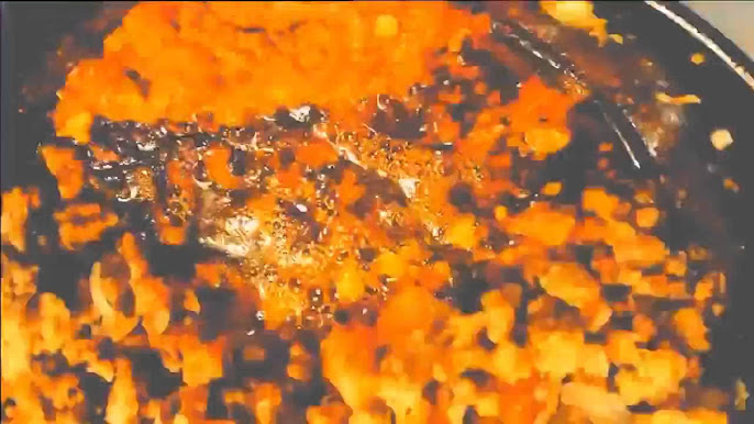 Sartén con una mezcla de ingredientes cocinándose a fuego lento, mostrando una textura dorada y burbujeante, ideal para recetas de guisos o salsas.